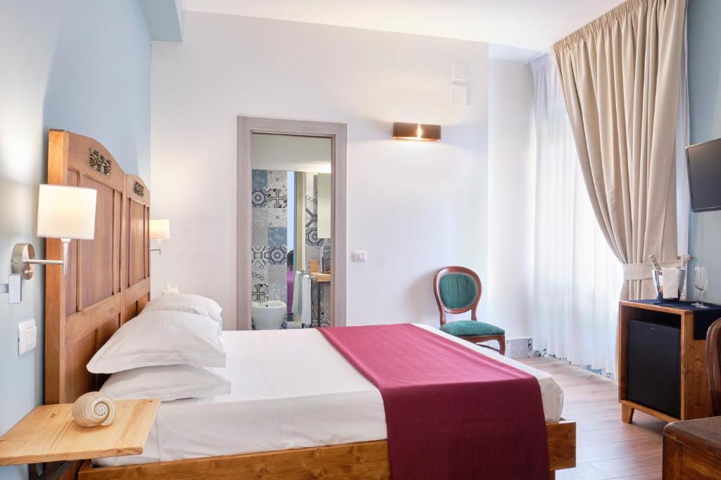 阿格罗波利La Via del Porto Charme Rooms的配有一张床和一把椅子的酒店客房