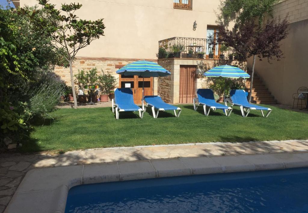 Castellote卡斯特略特酒店的一组椅子和遮阳伞,位于游泳池旁