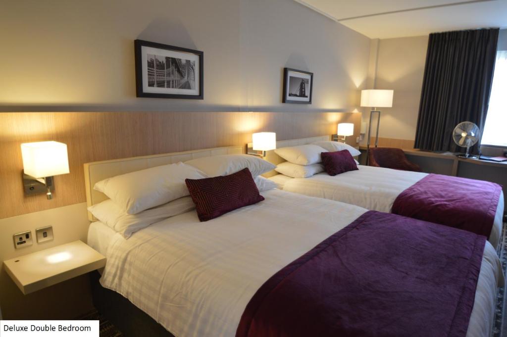 阿克斯桥Lancaster Hotel的酒店客房设有两张床和两盏灯。