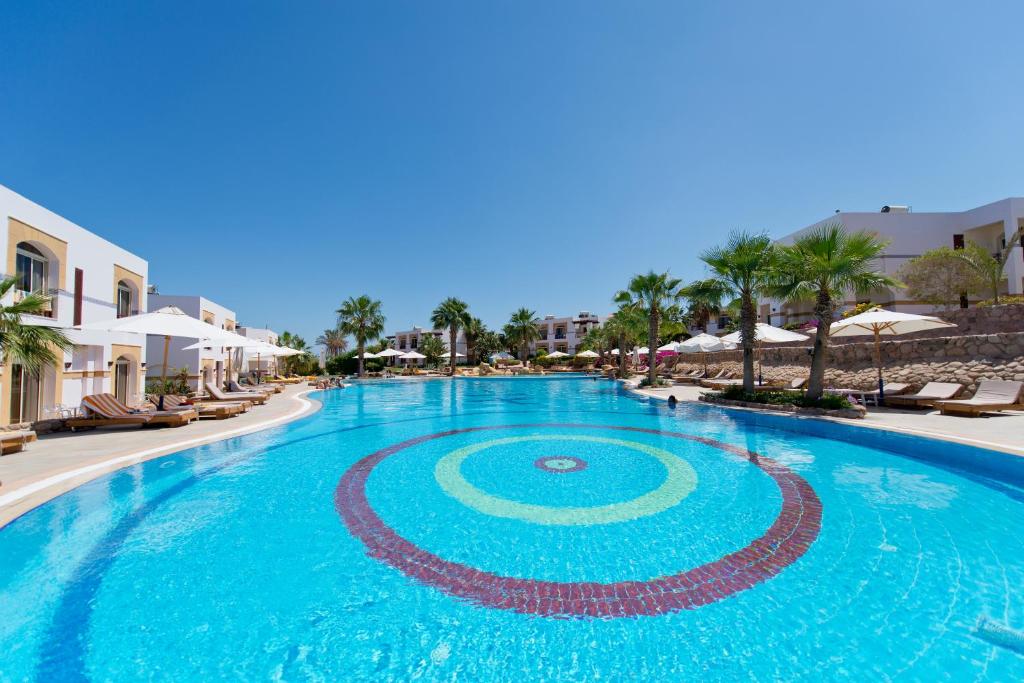 沙姆沙伊赫Amphoras Blu的度假村内的大型游泳池配有椅子和遮阳伞
