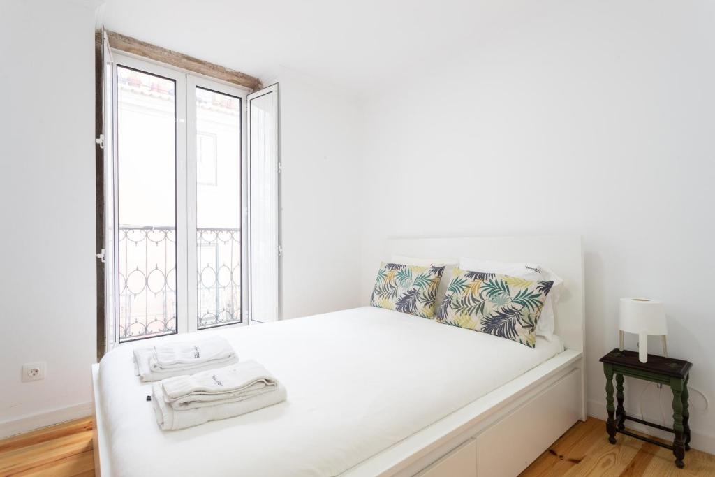里斯本FLH Mouraria Charming Flat II的窗户客房内的一张白色床
