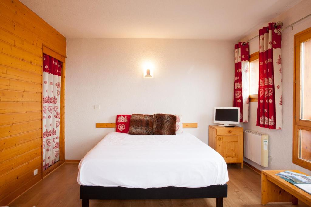 孔布卢弗洛拉普酒店的卧室配有白色的床和电视。
