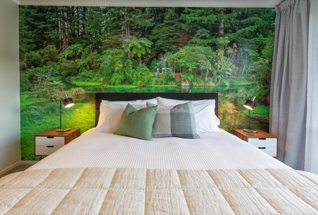 罗托鲁瓦Parkside Boutique Lodge的一间卧室配有一张带森林壁画的大床