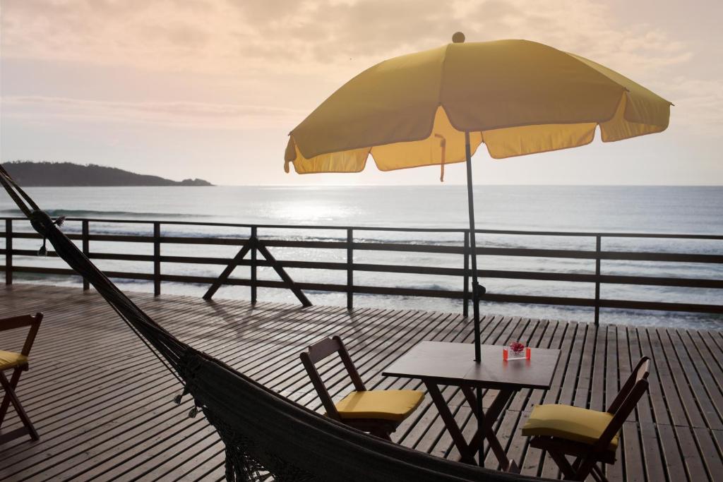 弗洛里亚诺波利斯Hibisco Guest House的一张桌子和椅子,配有雨伞和大海