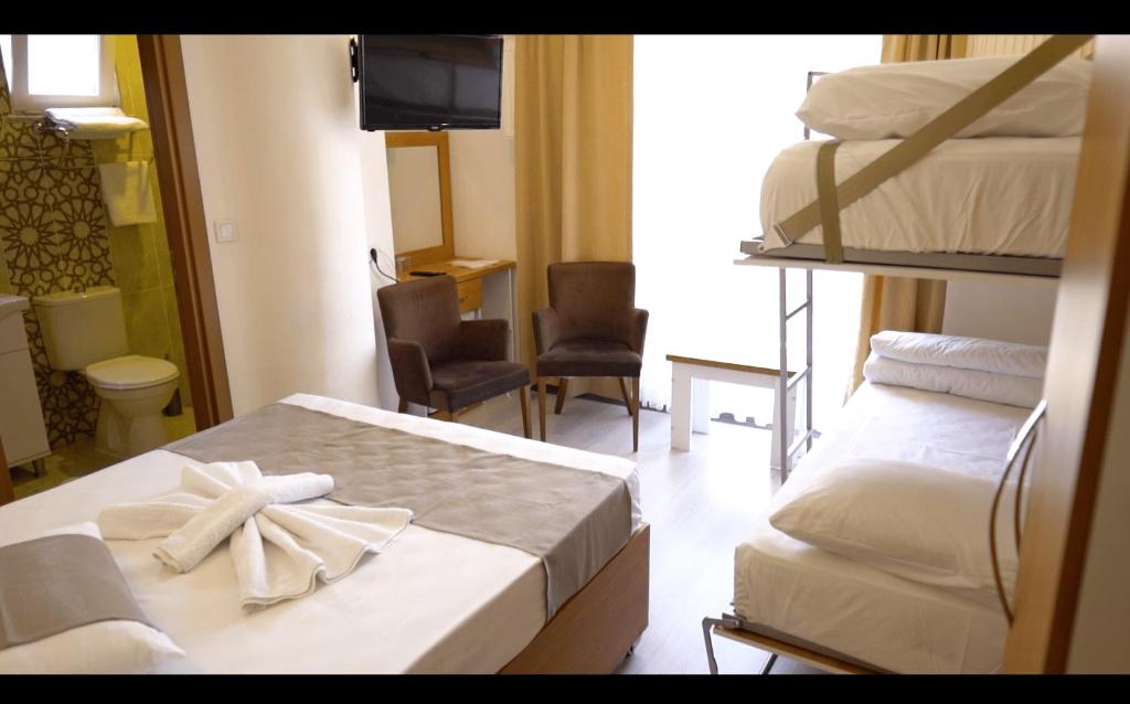 恰纳卡莱GÜVEN HOTEL的酒店客房设有两张双层床和电视。