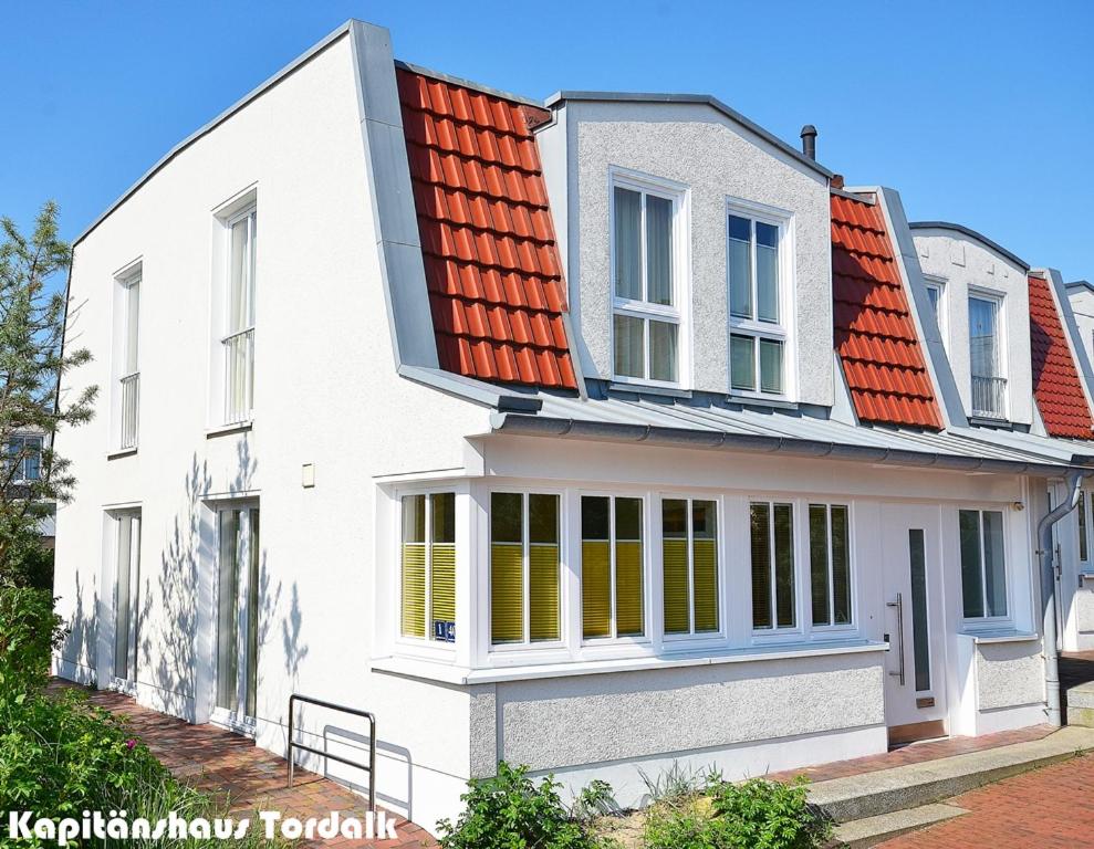诺德奈Kapitänshaus Tordalk mit 3 Schlafzimmern的白色房子,有橙色屋顶