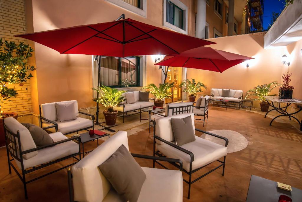罗马河畔城堡酒店的一个带桌椅和红色遮阳伞的庭院