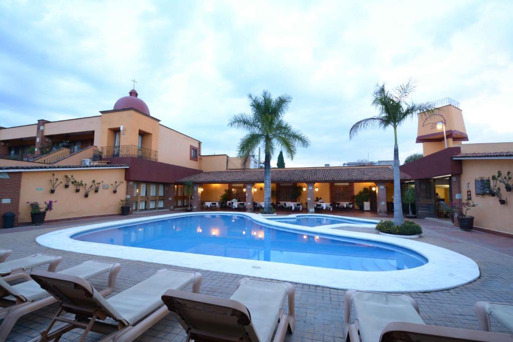 瓦哈卡市Hotel Hacienda的一座带椅子的建筑和一座度假村前的游泳池