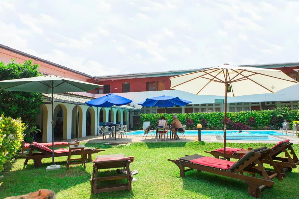 拉维尼亚山Ranveli Beach Resort的一个带桌子和遮阳伞的庭院和一个游泳池