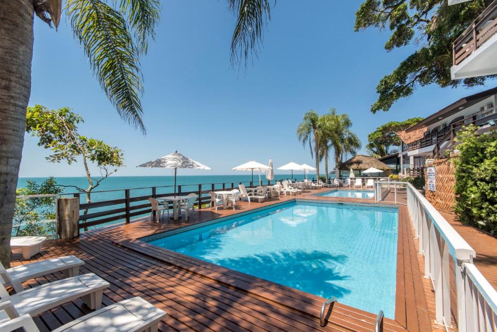 邦比尼亚斯Bombinhas Tourist Apart的一个带椅子的游泳池,背景是大海