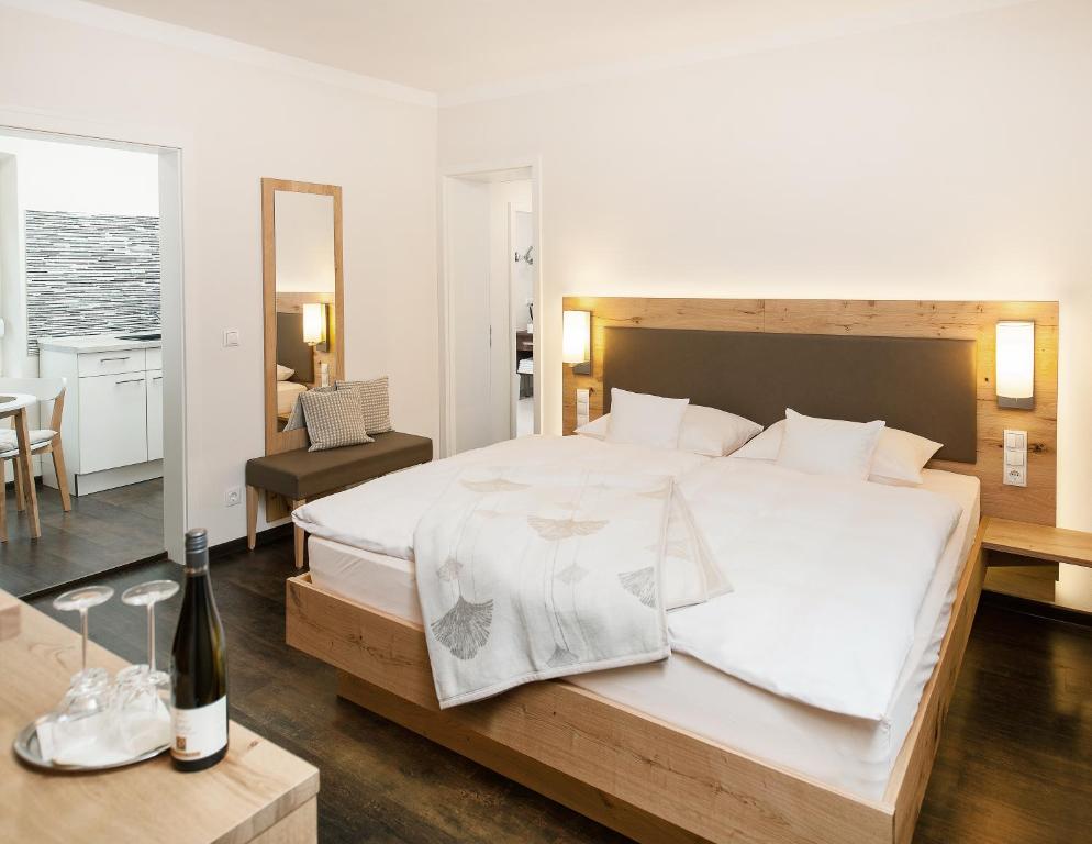 Flörsheim-DalsheimGästehaus & Weingut PETH的一间卧室配有一张大床和一张桌子及一瓶葡萄酒