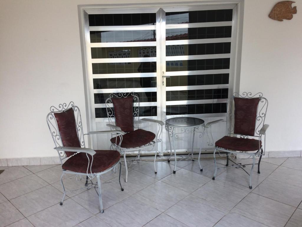 索莱马Casa, Praia e Lazer.的玻璃桌、四把椅子和窗户