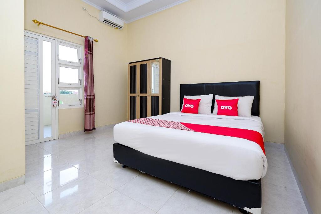 梭罗OYO 2058 Griya Ria的一间卧室配有一张带红色枕头的大床