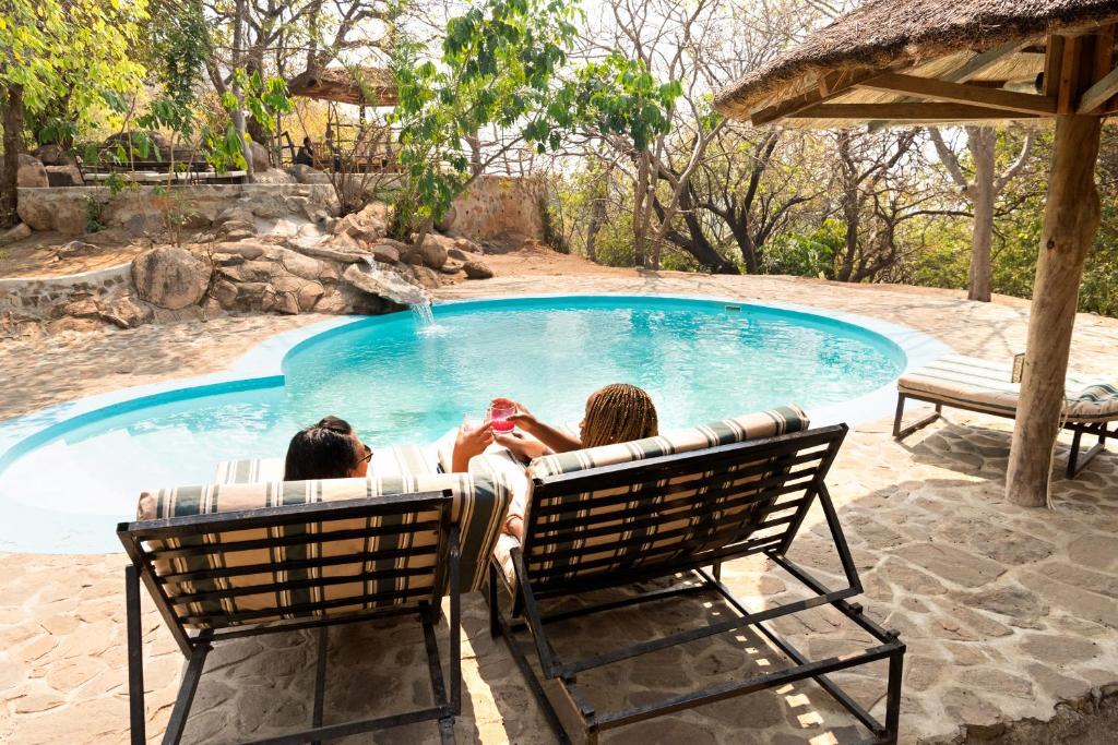 SengaSafari Beach Lodge的两人坐在游泳池前的椅子上
