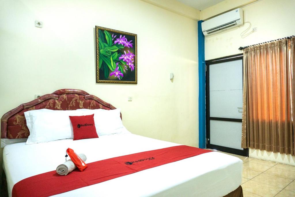 英德RedDoorz near H. Hasan Aroeboesman Airport的一间卧室配有一张带红色毯子的床