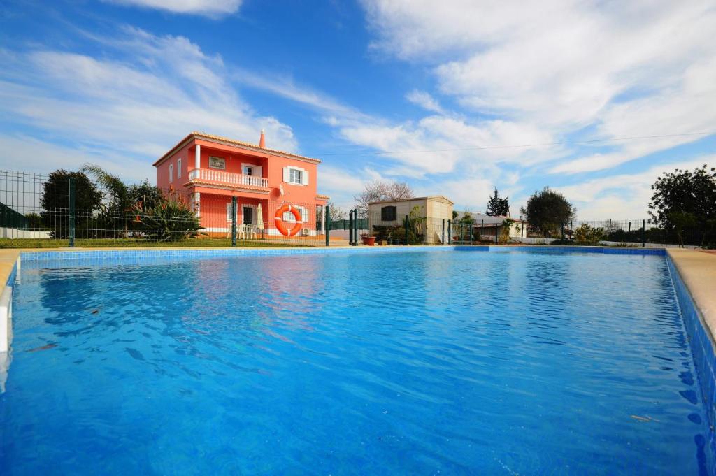 阿尔坎塔里利亚Villa Casa das Amendoeiras的粉红色建筑前的大型游泳池
