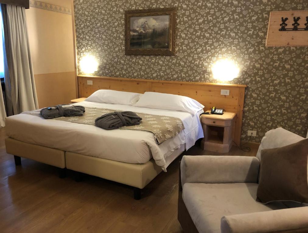 布勒伊-切尔维尼亚Hotel Edelweiss 3 Stelle SUPERIOR的一间卧室配有一张床、一把椅子和一张沙发