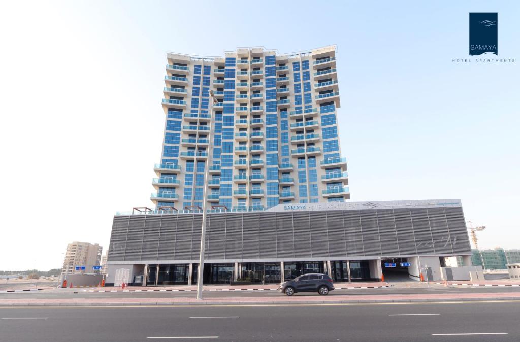 迪拜Samaya Hotel Apartment Dubai的停在大楼前的汽车