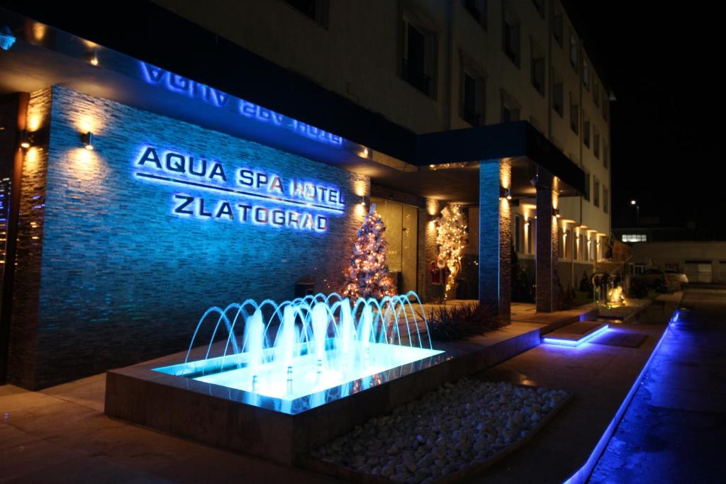 兹拉托格勒Aqua Spa Hotel Zlatograd的一座带圣诞树的建筑前的喷泉