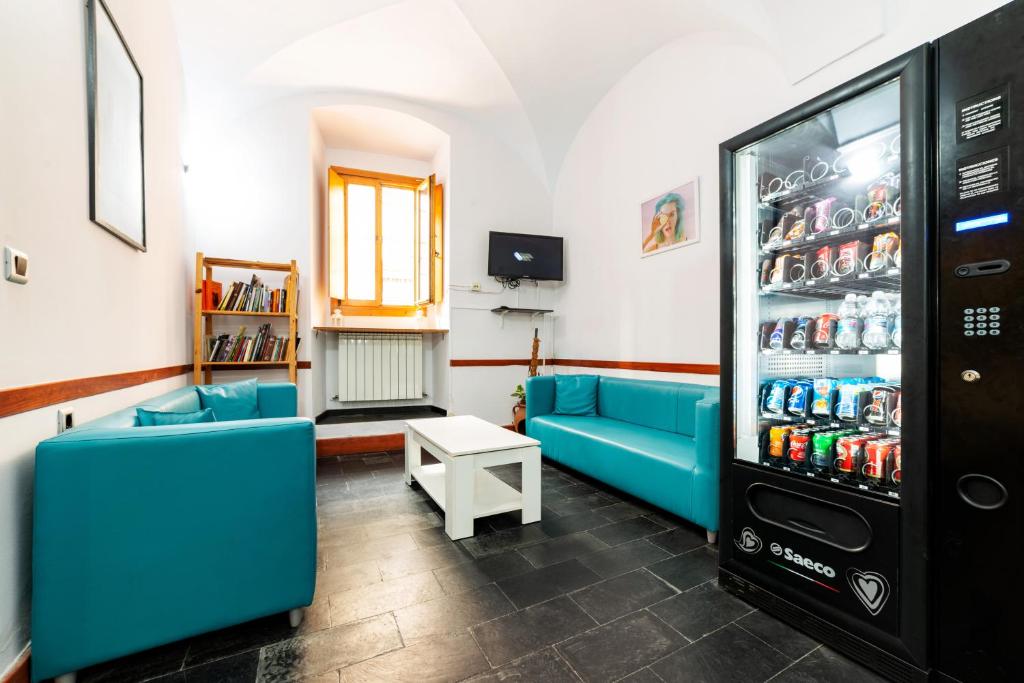 卡塞雷斯Albergue las Veletas的客房设有蓝色的沙发和带苏打水罐的冰箱。