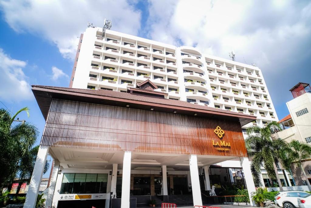 清迈La Mai Hotel的一间大型白色酒店,后面有一座建筑