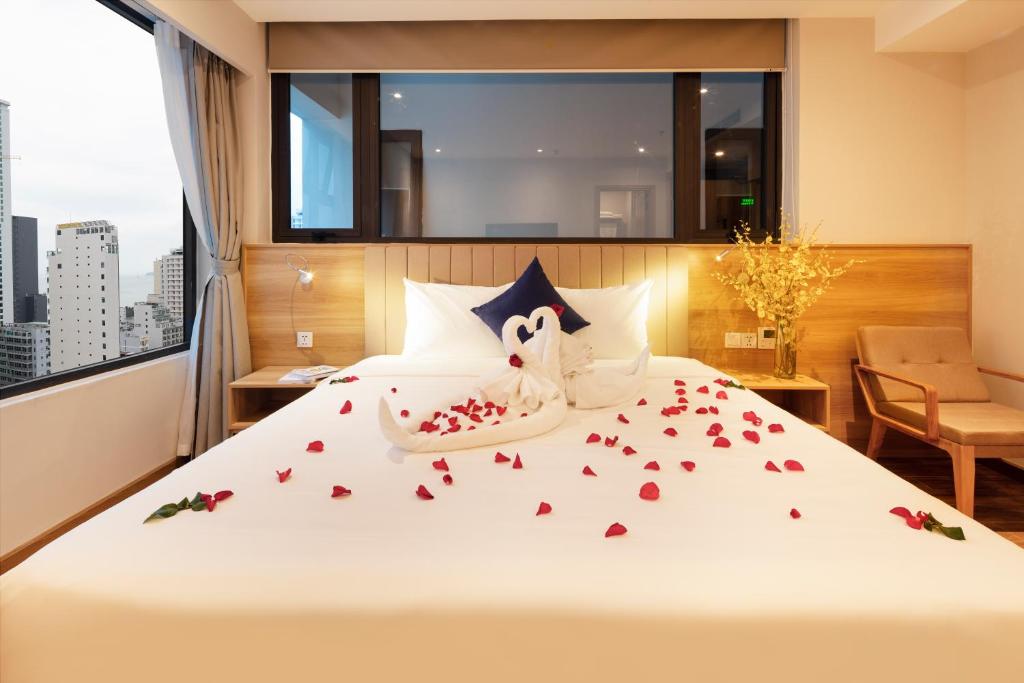 芽庄VENTANA NHA TRANG HOTEL的酒店客房的床铺上摆放着玫瑰花
