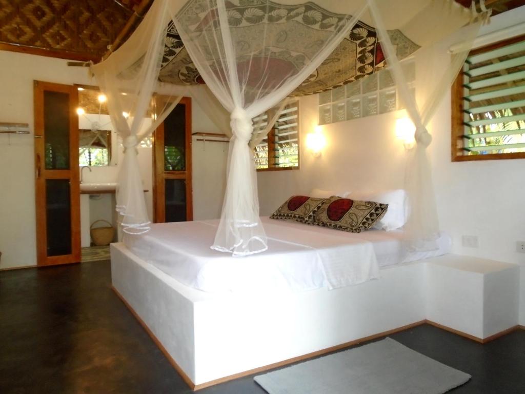 曼巴豪尼帕甘米银时尚度假村的一间卧室配有一张带天蓬的白色床