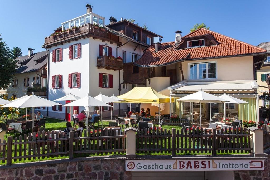 索普拉布扎诺Gasthaus Babsi的前面有桌子和伞的建筑