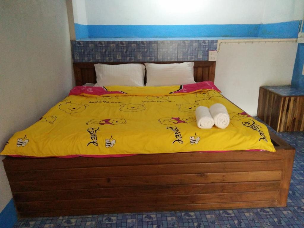 湄宏颂ปฎิภาณบ้านพัก的一张带黄床单的床和两张毛巾