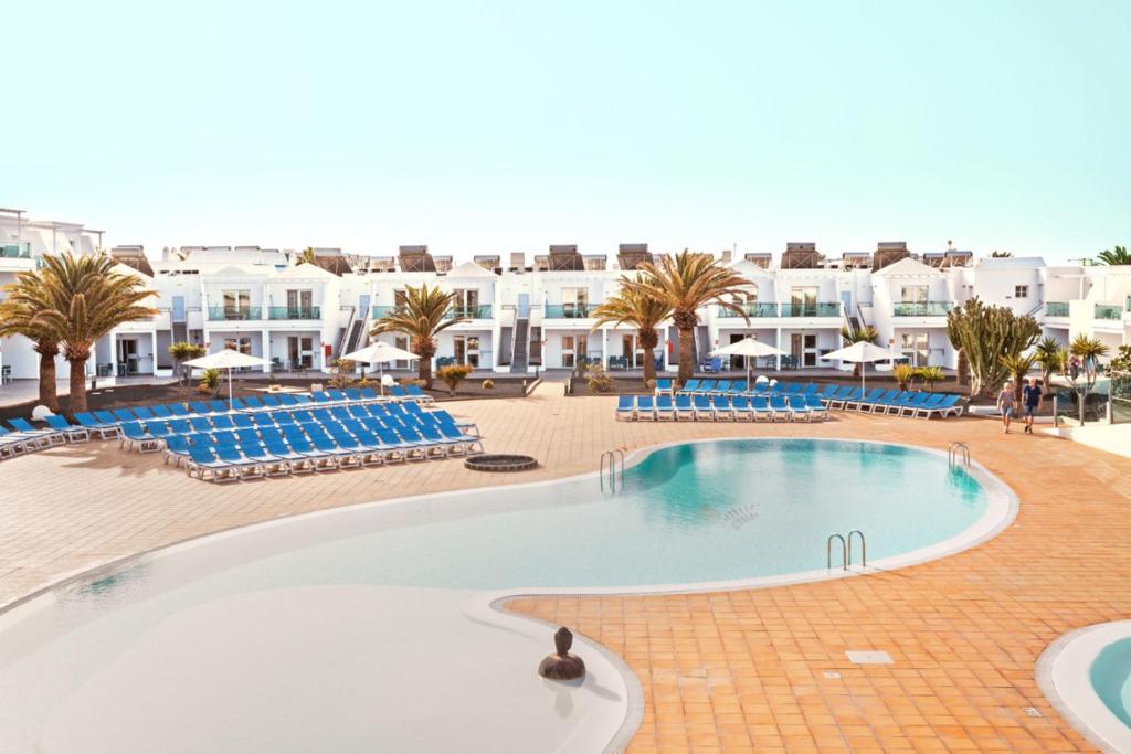 卡门港Blue Sea Lanzarote Palm的度假村内的大型游泳池,配有蓝色椅子