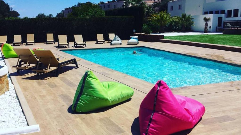 伊斯费古耶拉尔海滩Apartamentos Colomar的游泳池旁设有绿色和粉红色的椅子
