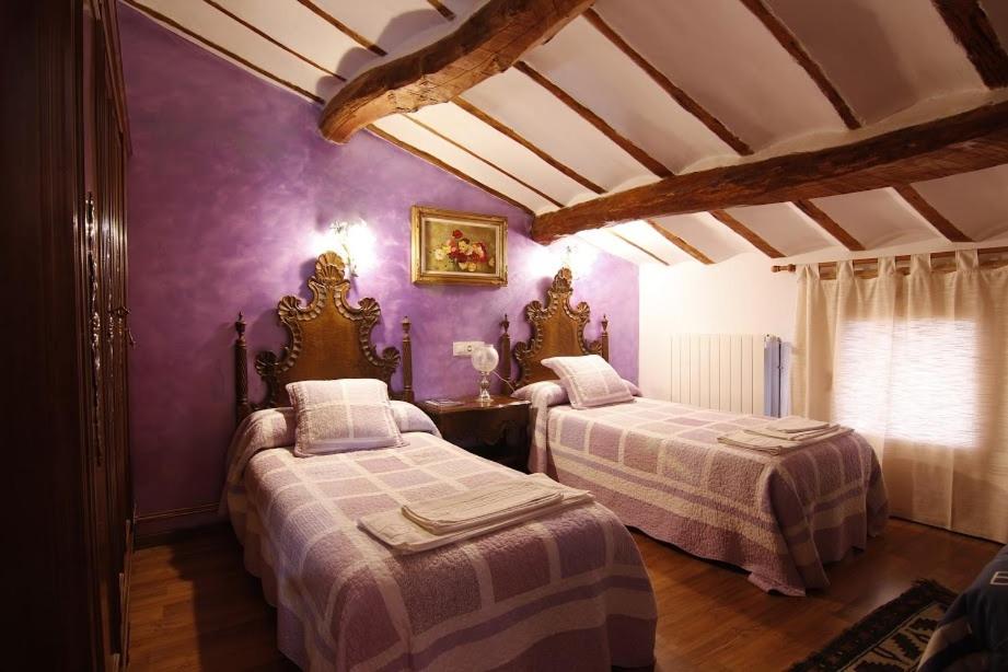 Cirueña维多利亚旅馆的紫色墙壁客房的两张床