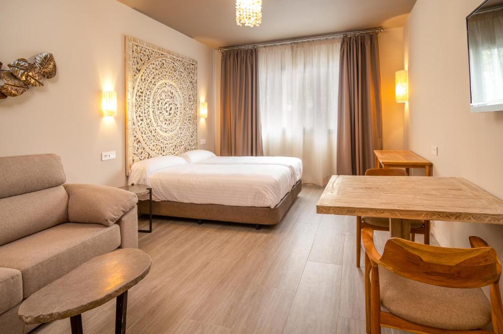 塞维利亚Apartamentos Sevilla Este by QHotels的酒店客房,配有床和沙发