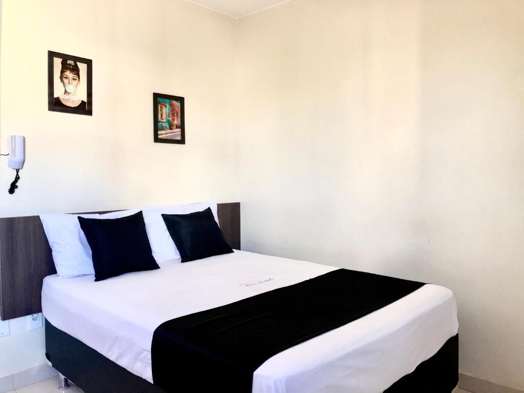 塔瓜汀加Paris Hotel by H Hotéis - Business的一间卧室配有一张大床,铺有黑白床单。
