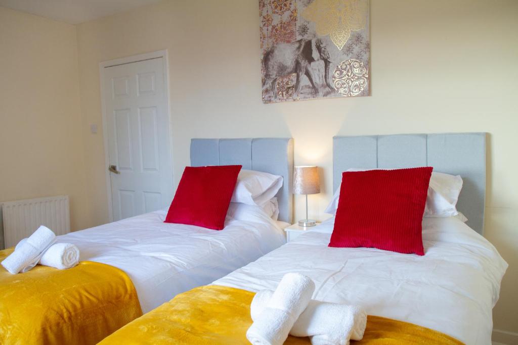 格兰奇茅斯Carvetii - Derwent House - Spacious 2nd floor flat的配有红色和白色枕头的客房内的两张床