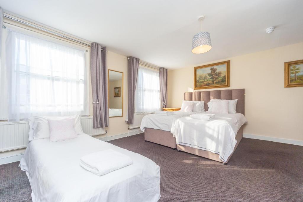 Surbiton黑狮子旅馆的一间卧室配有两张带白色床单的床