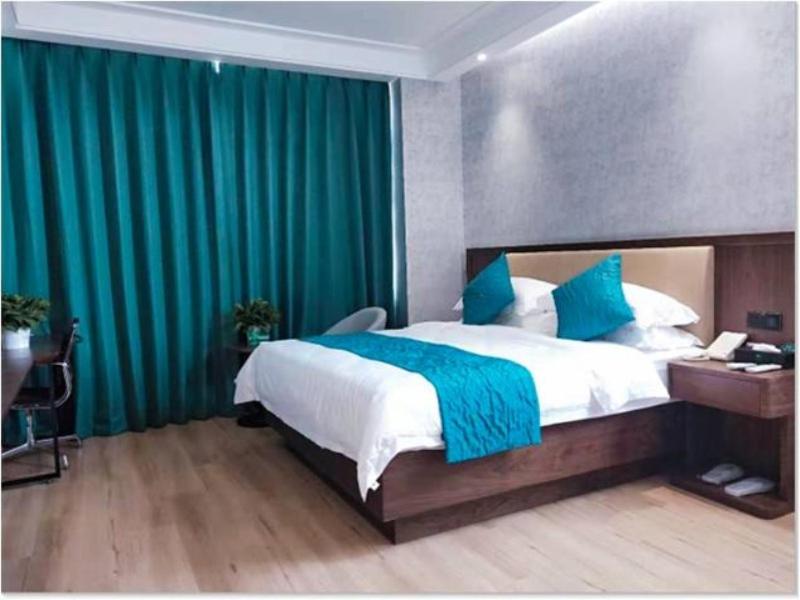 银川格林豪泰银川国际商贸城商务酒店的一间卧室配有一张带绿色窗帘的大床