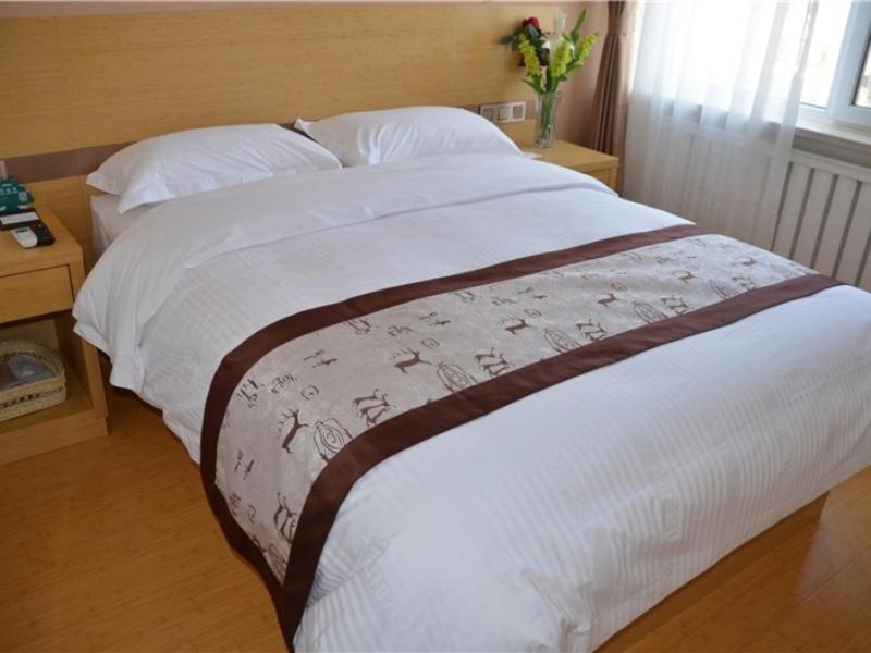 沈阳格林豪泰沈阳盛京医院滑翔地铁站商务酒店的一间卧室配有一张带白色床单和花瓶的床。