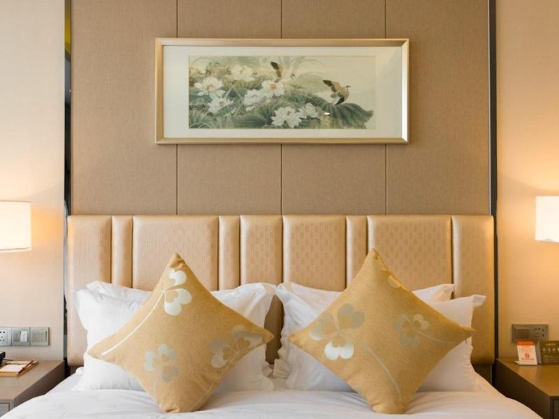 无锡格林东方无锡新区假日广场酒店的一张带枕头的床和墙上的照片