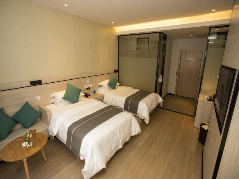 玉林格林豪泰玉林会展中心大润发酒店的酒店客房设有两张床和一张桌子。