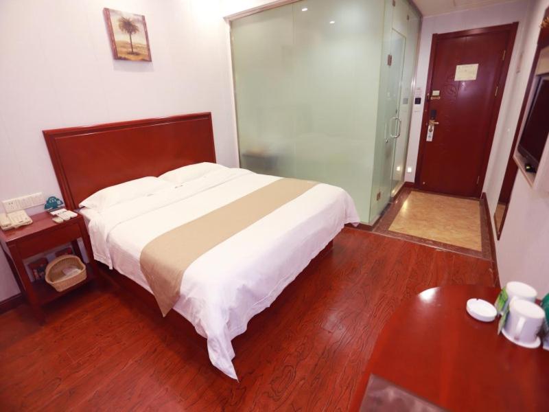 银川格林豪泰银川市步行街新华百货商务酒店的一间卧室设有一张大床和一个玻璃门