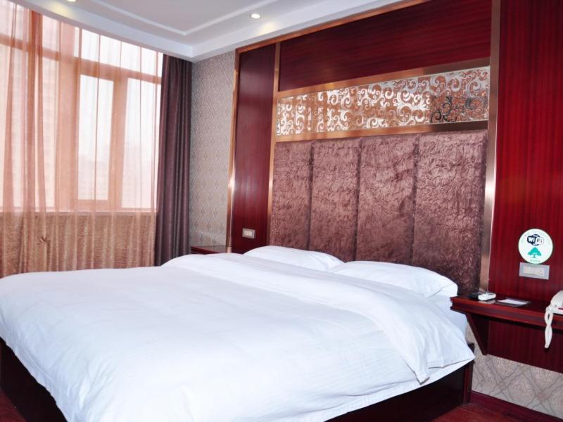 兰州格林豪泰兰州火车站客运中心商务酒店	的卧室配有一张白色大床和木制床头板