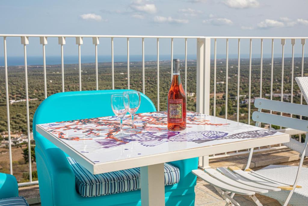 奥斯图尼Dimore del TEMPO PERS0 Mare videre的阳台上的桌子上放有一瓶葡萄酒和玻璃杯