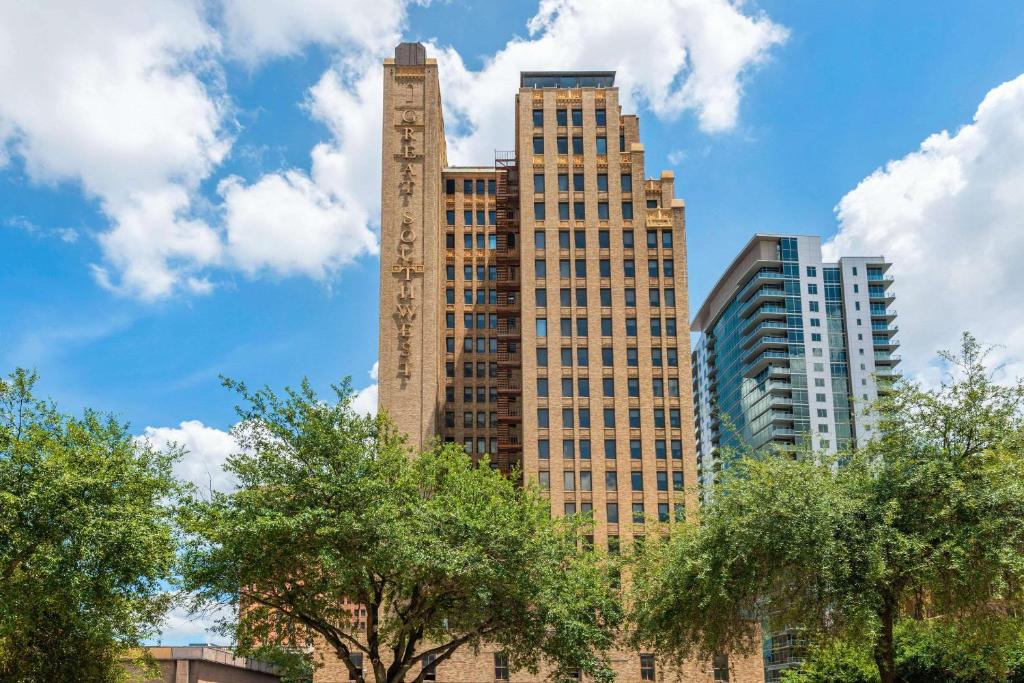 休斯顿Cambria Hotel Houston Downtown Convention Center的一座高大的建筑,在建筑前方有树木