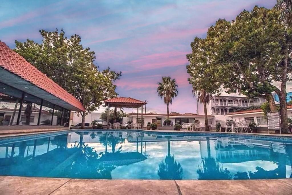 奇瓦瓦波萨达迪瑞布兰卡酒店的一座树木繁茂的建筑前的游泳池
