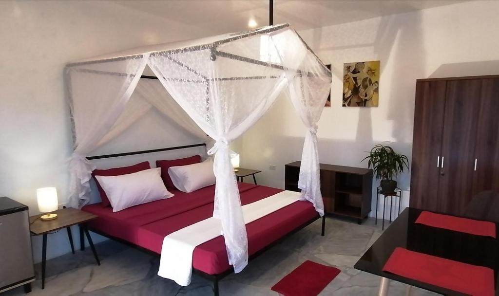 RomblonLonos Circle Private Garden的卧室配有红色和白色的床和天蓬
