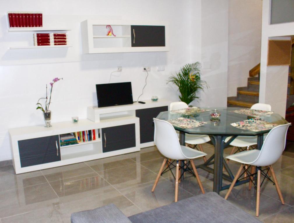 瓦伦西亚Apartamento Luminoso cerca de la PLAYA y PUERTO的一间设有玻璃桌和白色椅子的用餐室