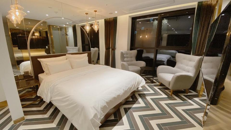 首尔Hotel the Castle Banyi的卧室配有一张白色大床和椅子