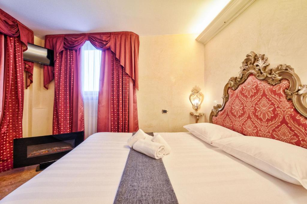 威尼斯Hotel Vecellio Venice on the Lagoon的一间卧室配有一张带红色窗帘的大床