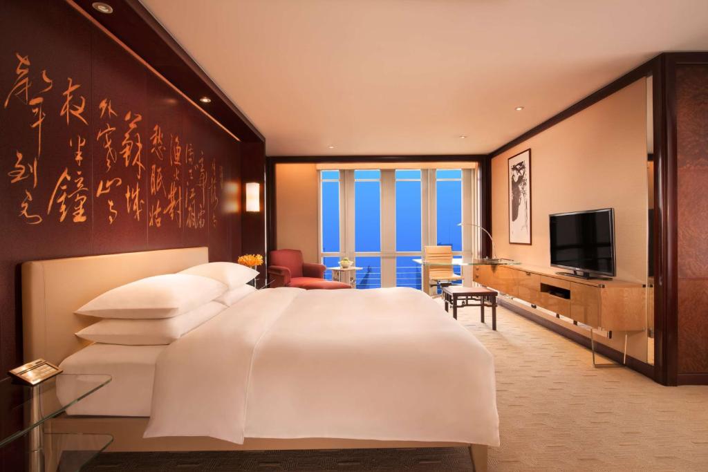 上海上海金茂君悦大酒店的卧室配有一张白色大床和电视。